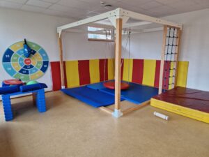 Turnraum mit Schaukelgerüst, Kletterwand, bunten Matten und Zielscheibe